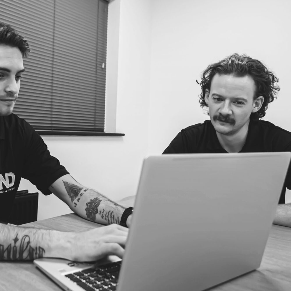 Two Net-Defence team members around a laptop