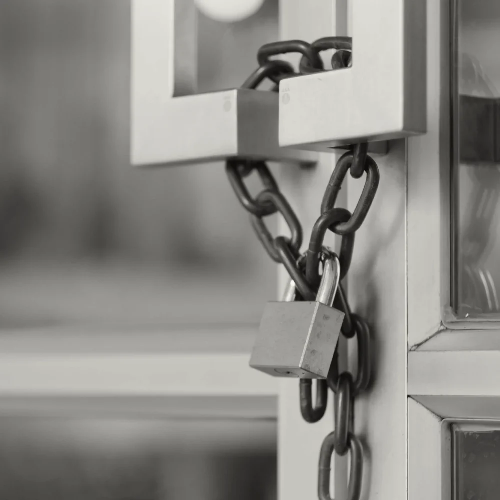 A padlock and chain wrapped around the door handles of a glass door.