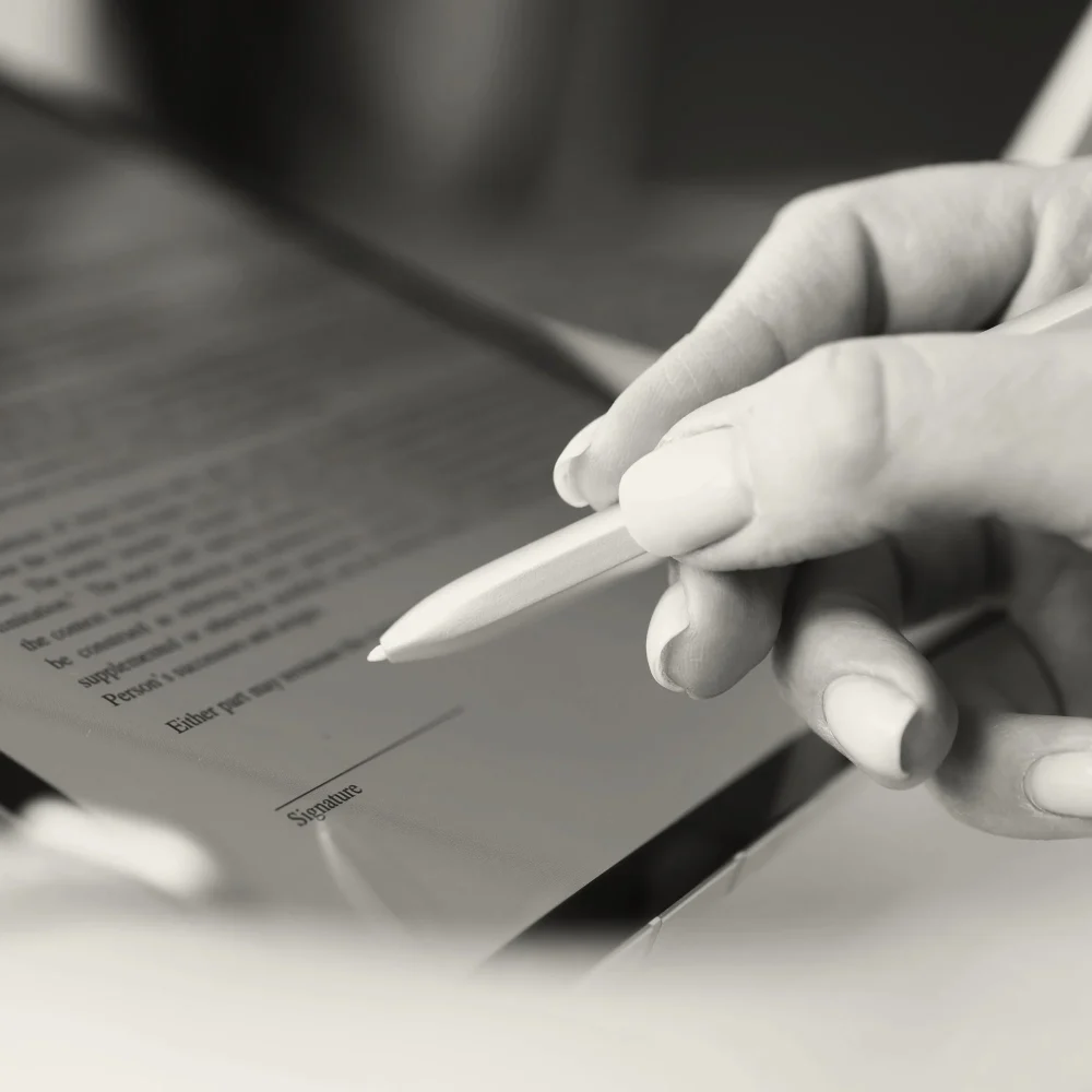A woman's hand gripping a stylus to write her digital signature.